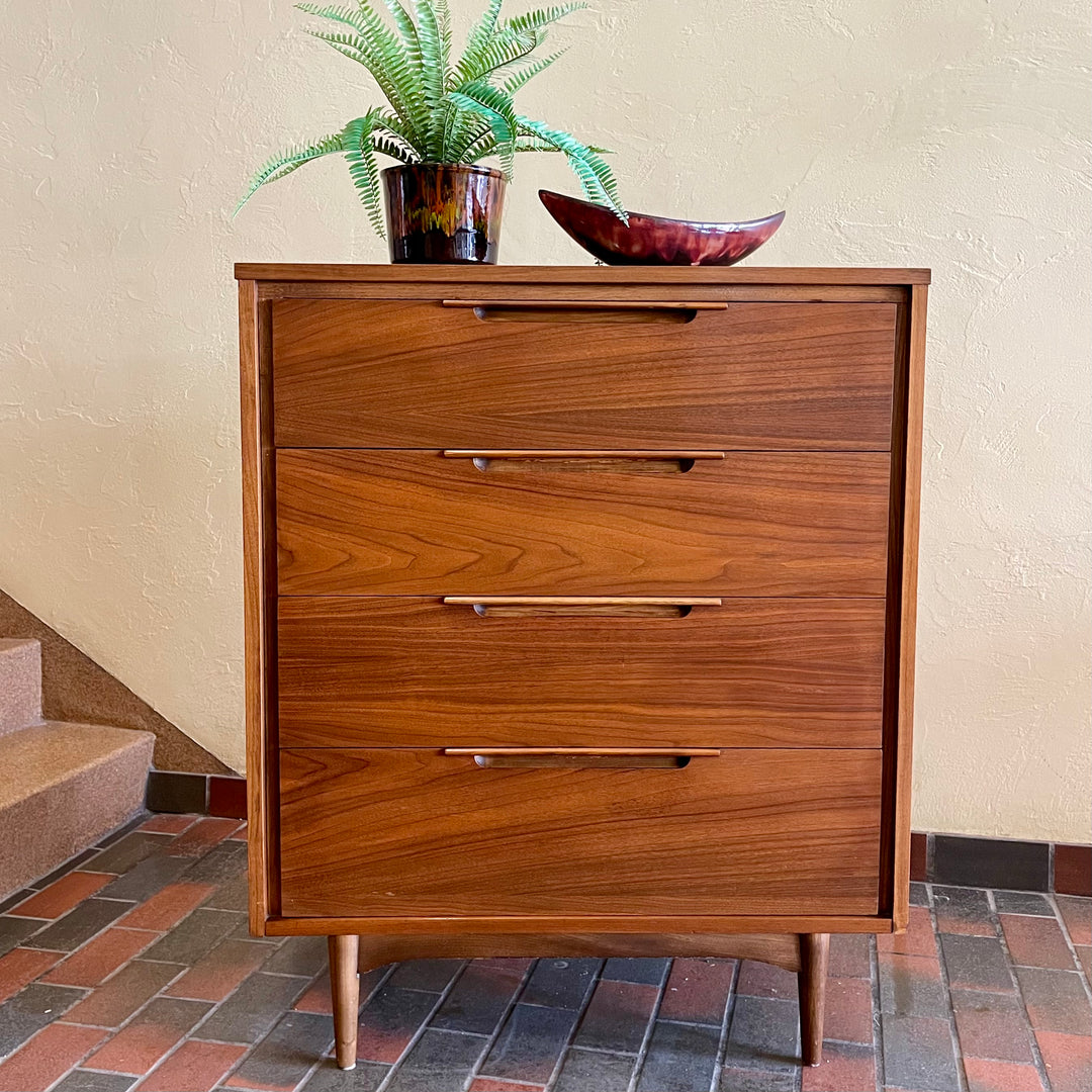 This Vintage KRUG Walnut Tallboy Dresser features four drawers and is made of rich dark walnut wood. Its classic design and high-quality construction make it a timeless addition to any bedroom. 