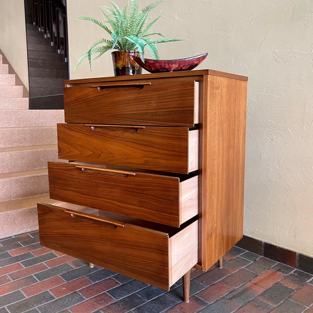This Vintage KRUG Walnut Tallboy Dresser features four drawers and is made of rich dark walnut wood. Its classic design and high-quality construction make it a timeless addition to any bedroom. 