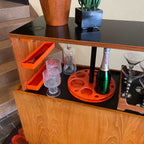 Interior of Danish teak pop-up bar cabinet showing bottle and glassware storage