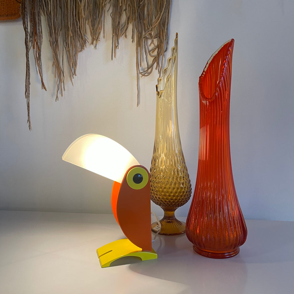 Colorful vintage toucan table lamp with glowing white shade, orange body and yellow base