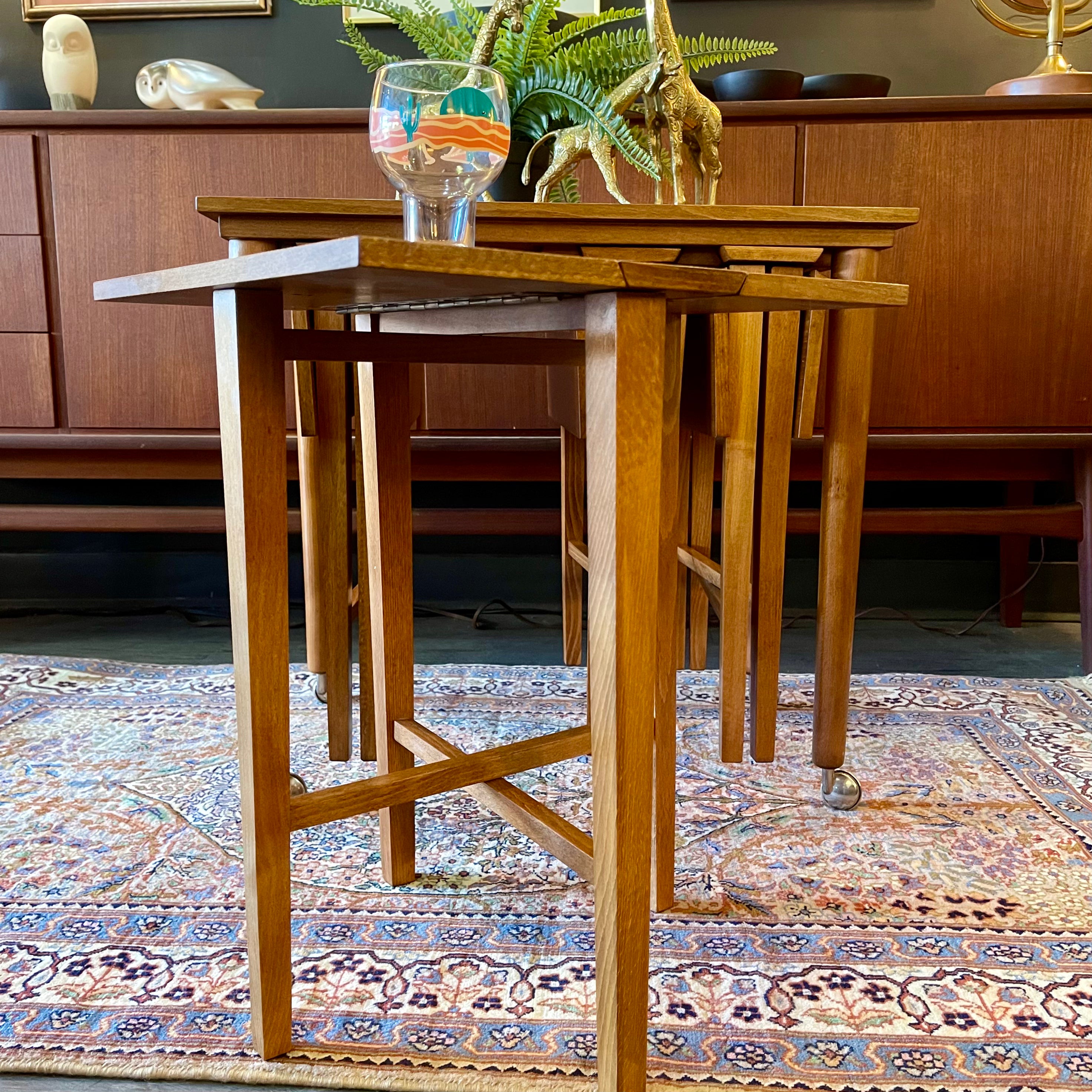 Mid Century Poul Hundevad Nesting Tables, a timeless and versatile addition to your living space. This exquisite set consists of five tables, with four of them ingeniously designed as drop-leaf tables that effortlessly slide beneath the main table, offering both functionality and aesthetic appeal.