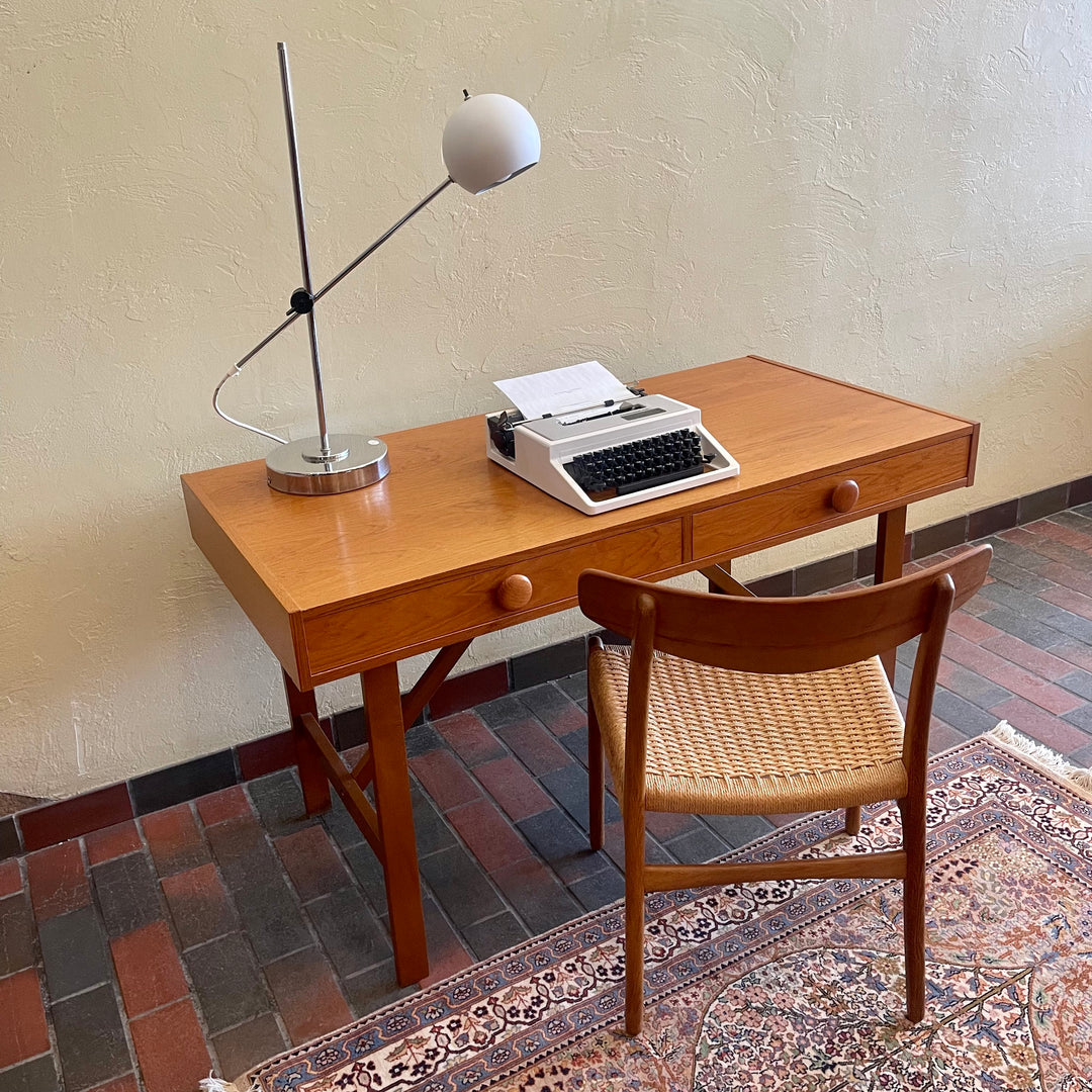  This Mid Century Danish Teak Desk epitomizes timeless design with its sleek lines and warm teak wood. Featuring two drawers, it offers practical storage while maintaining a minimalist aesthetic.