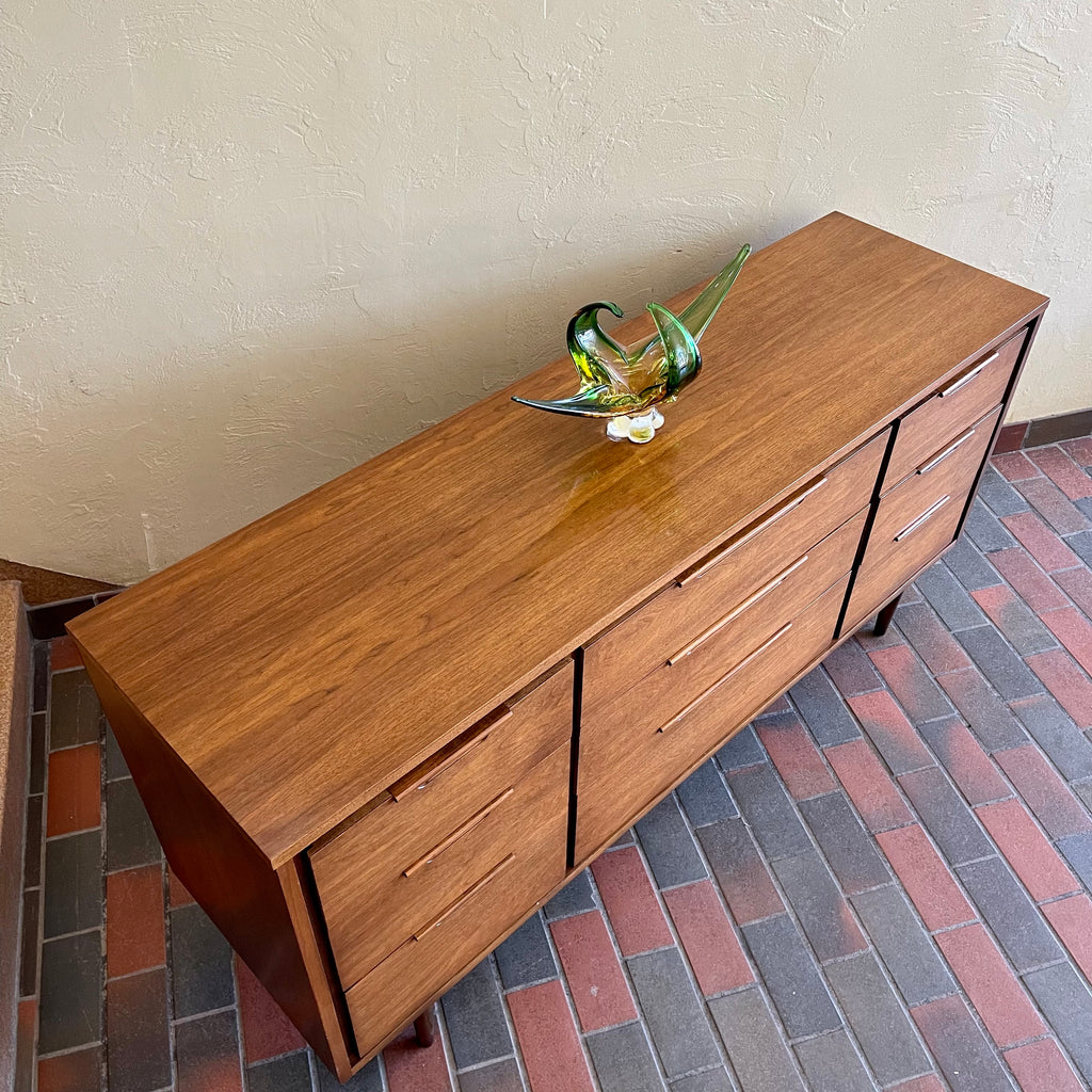 Enhance your bedroom with this Vintage KRUG Walnut 9 Drawer Dresser. The warm, rich color of the walnut complements any decor. Its sleek handle pulls add a touch of elegance to the design. With 9 spacious drawers, this dresser provides ample storage. 