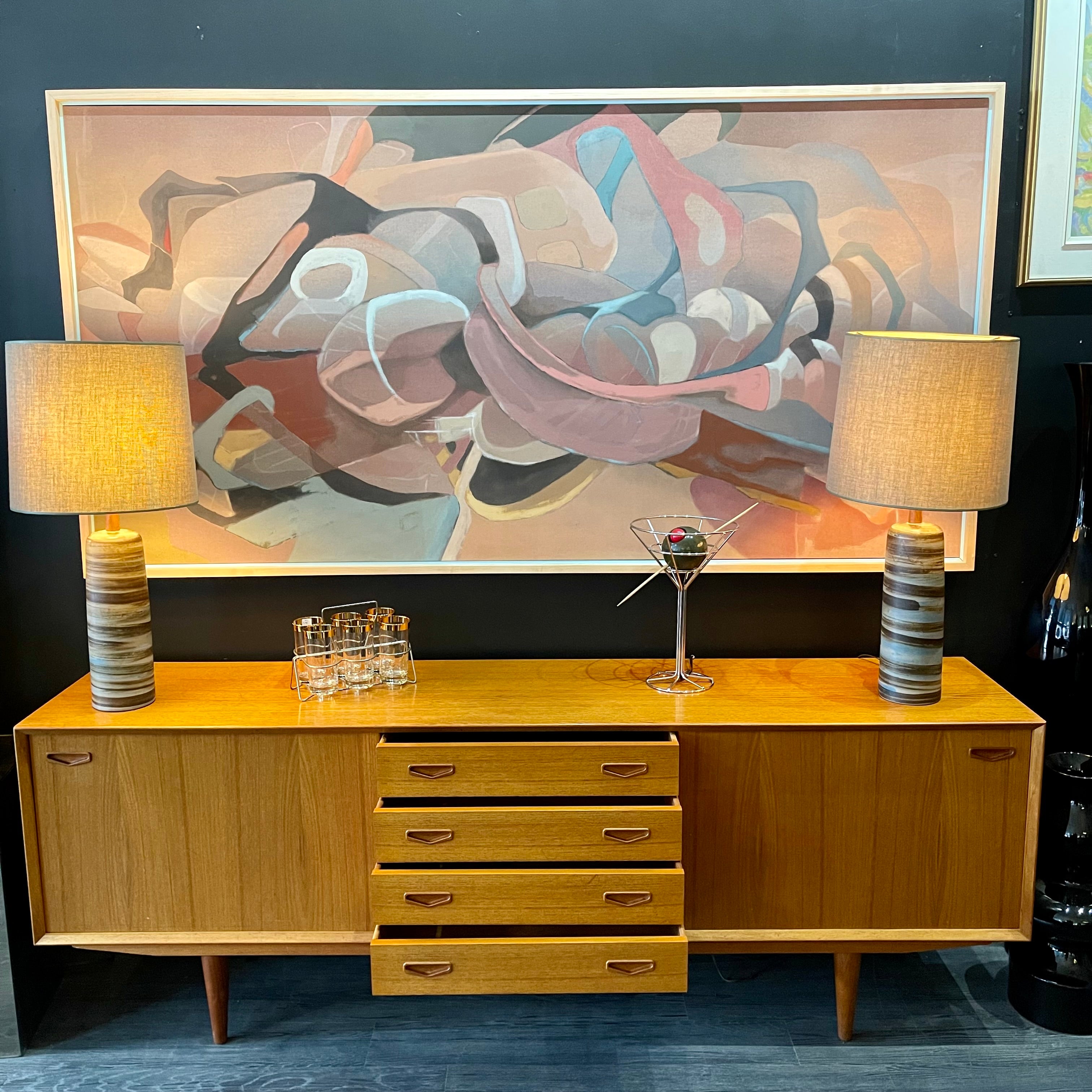 1960s Danish Teak Credenza is a beautiful blend of mid-century design and functionality. Crafted from teak, it features two sliding doors on either side that open to reveal ample storage space with adjustable shelving