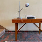  This Mid Century Danish Teak Desk epitomizes timeless design with its sleek lines and warm teak wood. Featuring two drawers, it offers practical storage while maintaining a minimalist aesthetic.