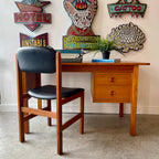 Mid-century teak desk with round drawer pulls, tapered legs and matching black upholstered chair