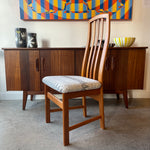 Load image into Gallery viewer, Teak dining chair with patterned cushion in front of a wooden cabinet with decorative items and a colorful abstract painting.
