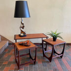 Teak G Plan nesting tables. Chrome Lamp with black shade, fern plant and an ashtray sits on top.There are 2 tables that pull out from under the main tablw. 