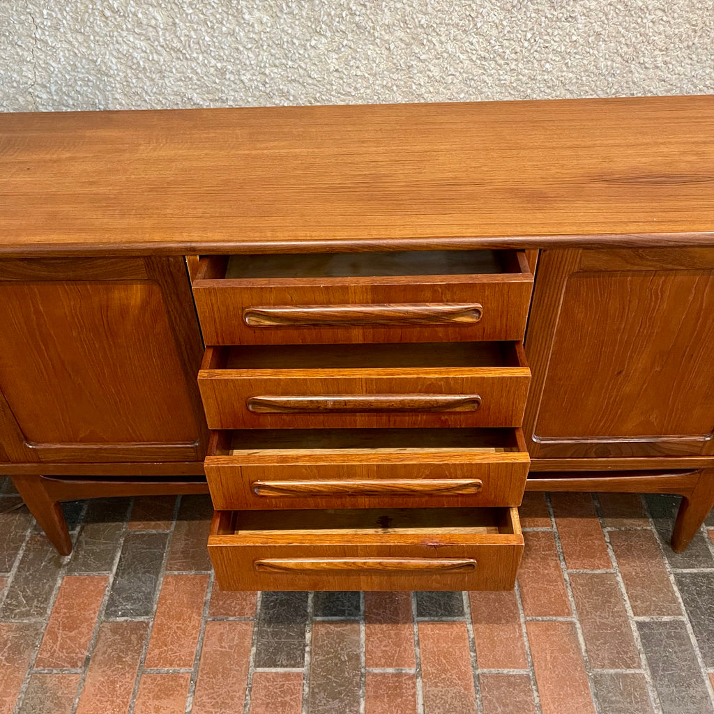 Crafted with attention to detail, this Mid Century Modern "Fresco" Teak Credenza by G Plan features four dovetail drawers for convenient storage, seamlessly integrated with additional storage on either side, offering even more organizational space.