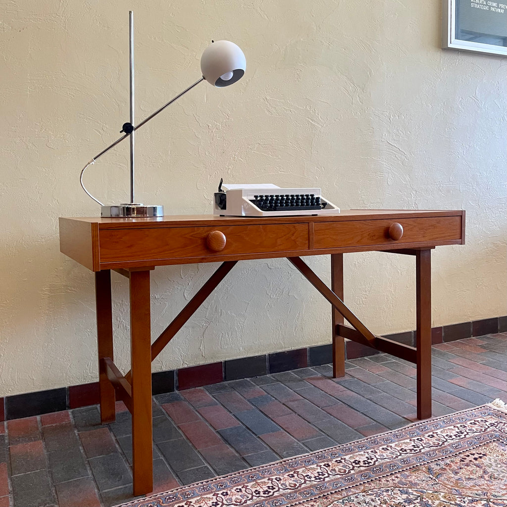  This Mid Century Danish Teak Desk epitomizes timeless design with its sleek lines and warm teak wood. Featuring two drawers, it offers practical storage while maintaining a minimalist aesthetic.