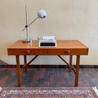  This Mid Century Danish Teak Desk epitomizes timeless design with its sleek lines and warm teak wood. Featuring two drawers, it offers practical storage while maintaining a minimalist aesthetic.