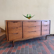 Enhance your bedroom with this Vintage KRUG Walnut 9 Drawer Dresser. The warm, rich color of the walnut complements any decor. Its sleek handle pulls add a touch of elegance to the design. With 9 spacious drawers, this dresser provides ample storage. 