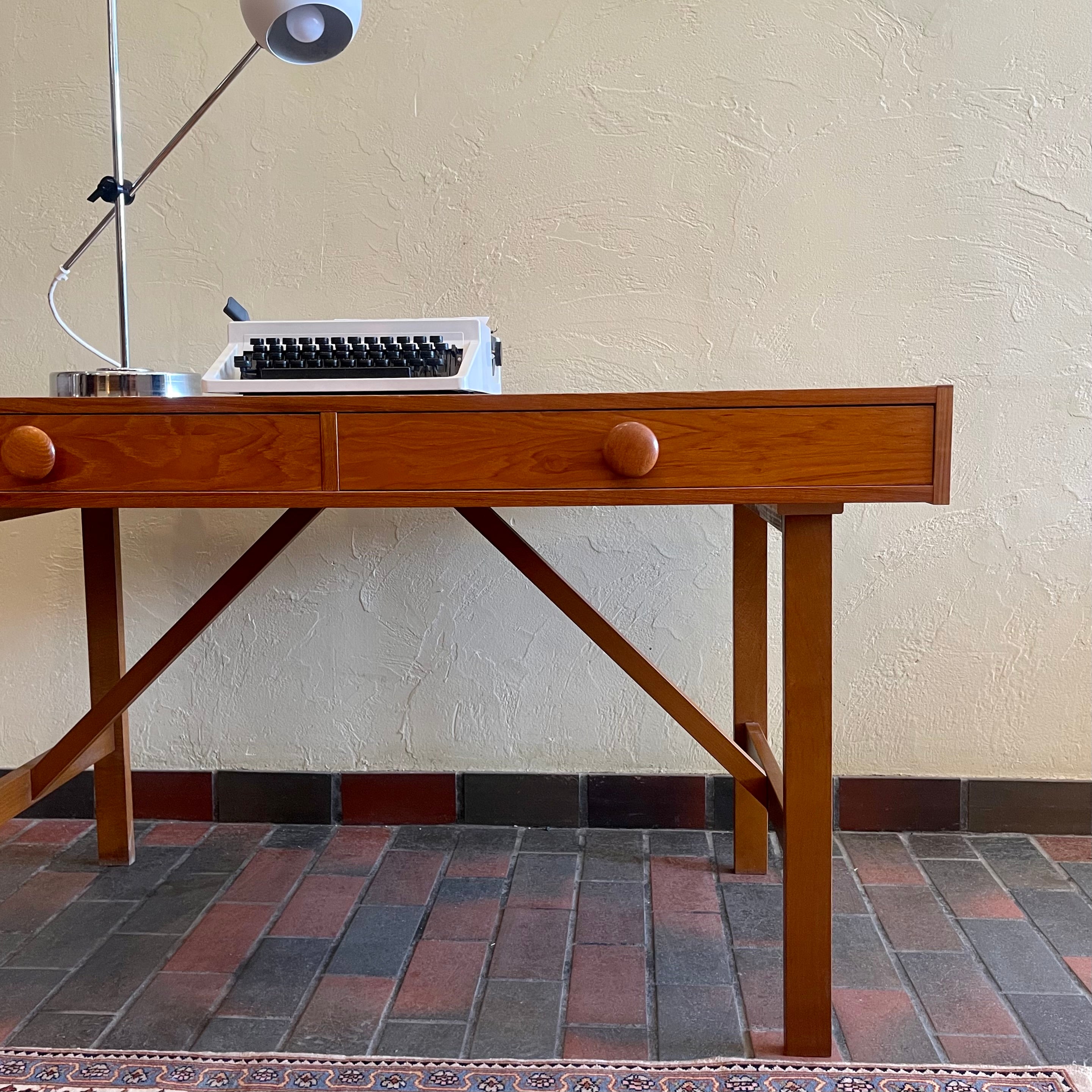  This Mid Century Danish Teak Desk epitomizes timeless design with its sleek lines and warm teak wood. Featuring two drawers, it offers practical storage while maintaining a minimalist aesthetic.