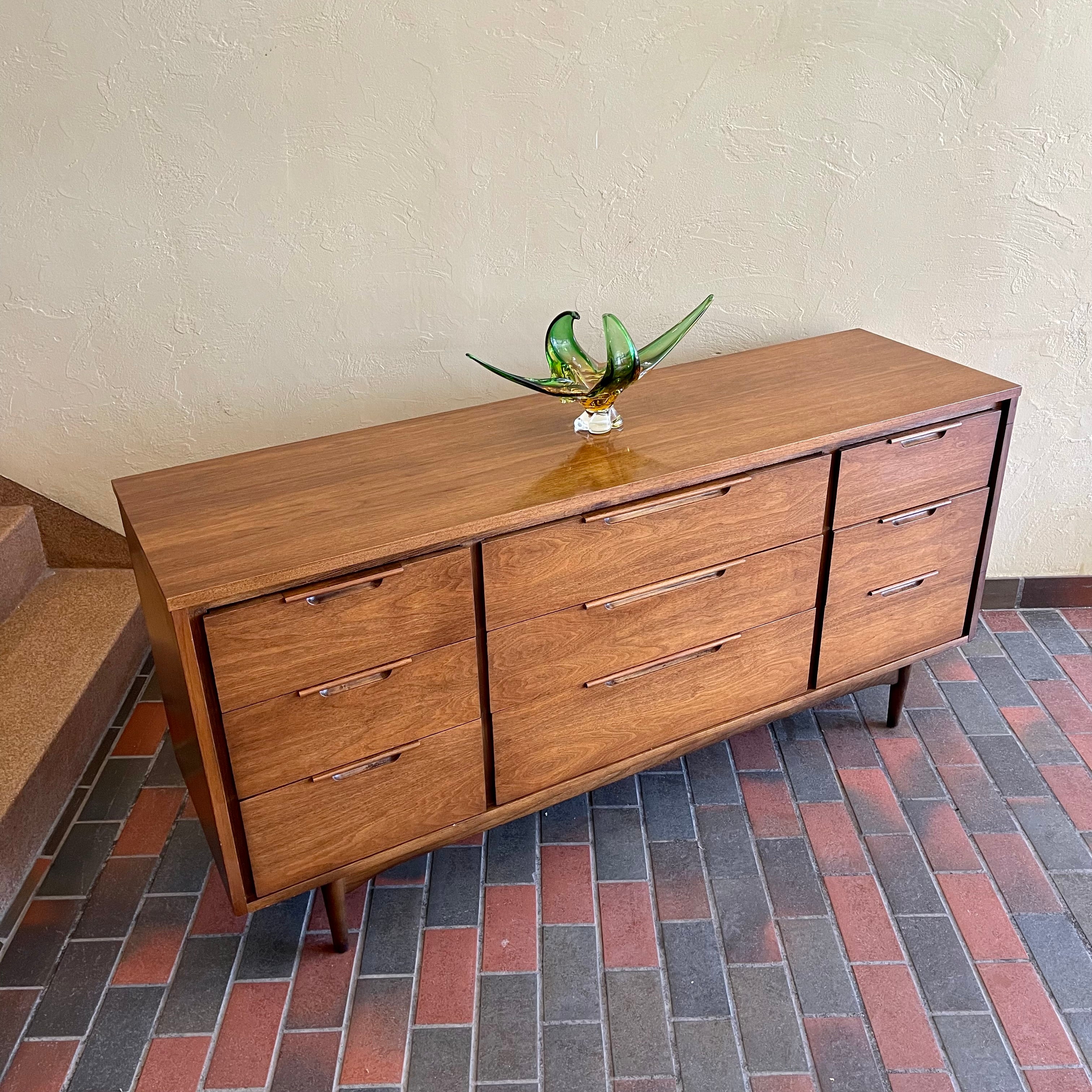 Enhance your bedroom with this Vintage KRUG Walnut 9 Drawer Dresser. The warm, rich color of the walnut complements any decor. Its sleek handle pulls add a touch of elegance to the design. With 9 spacious drawers, this dresser provides ample storage. 