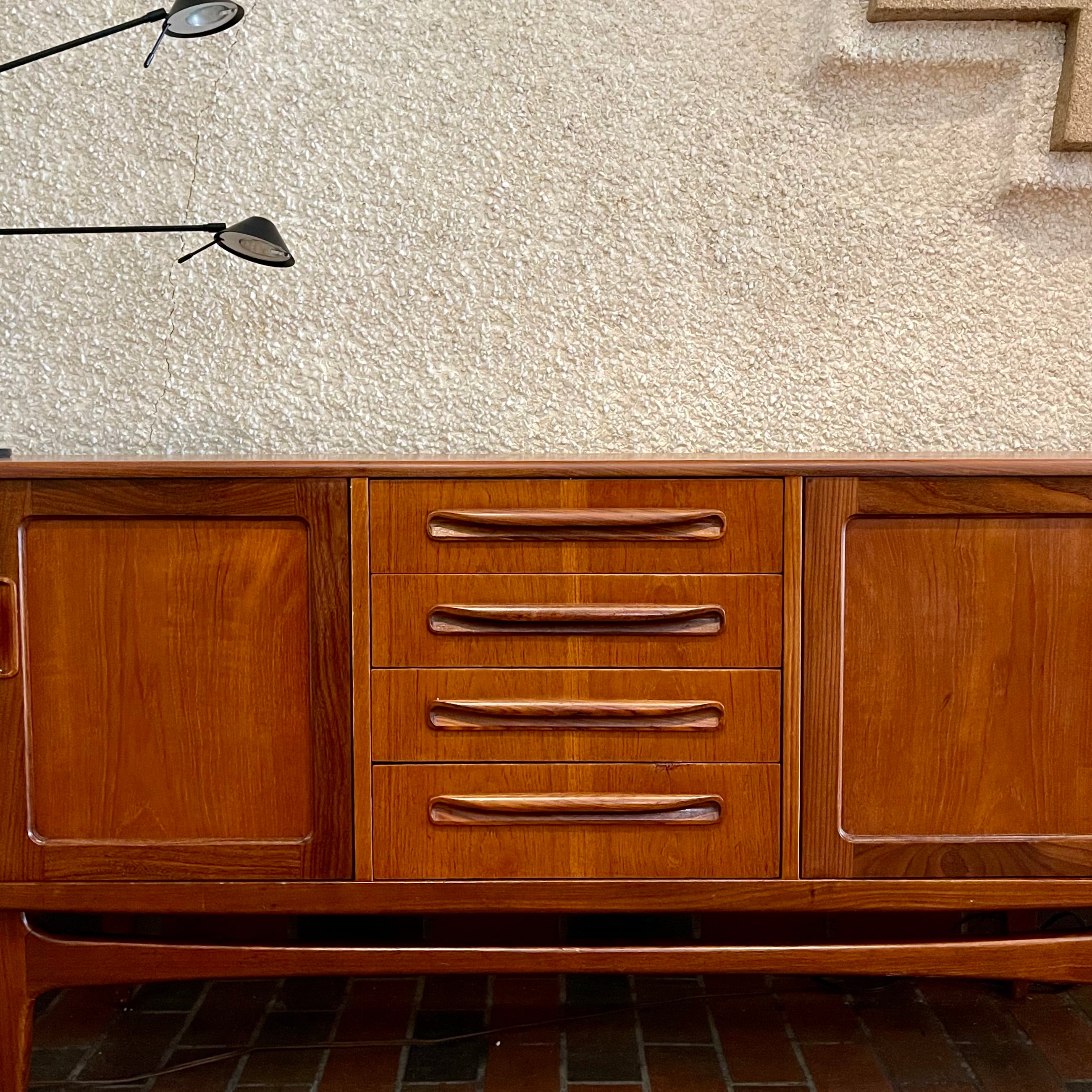Crafted with attention to detail, this Mid Century Modern "Fresco" Teak Credenza by G Plan features four dovetail drawers for convenient storage, seamlessly integrated with additional storage on either side, offering even more organizational space.
