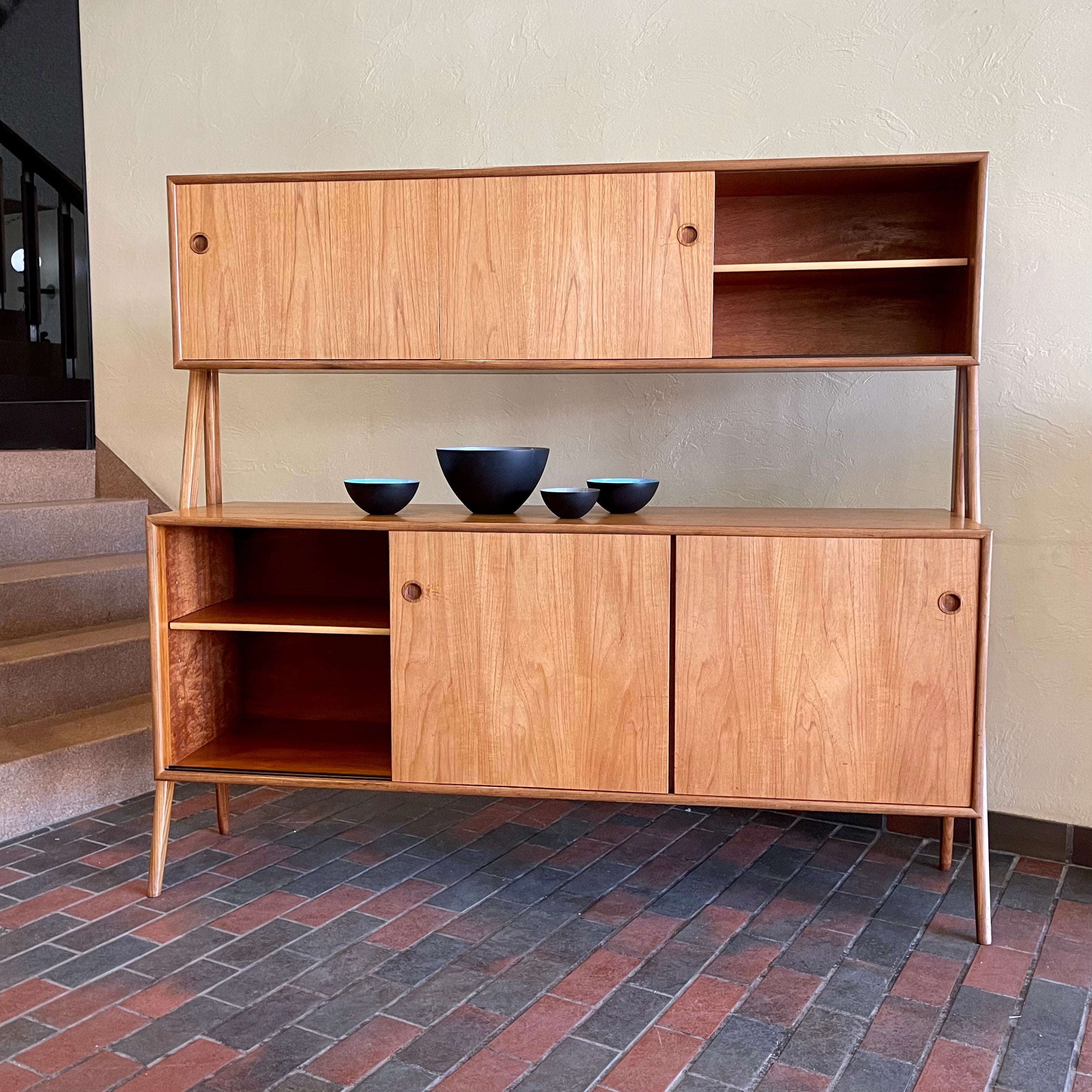 Two-tier Teak Danish Sideboard Credenza. The upper tier hosts a cabinet with sliding doors for storage. Below, sliding doors open to compartments with adjustable shelves, and drawers for small items. Solid sculptural teak legs tie the piece together. | Mr. Mansfield Vintage.