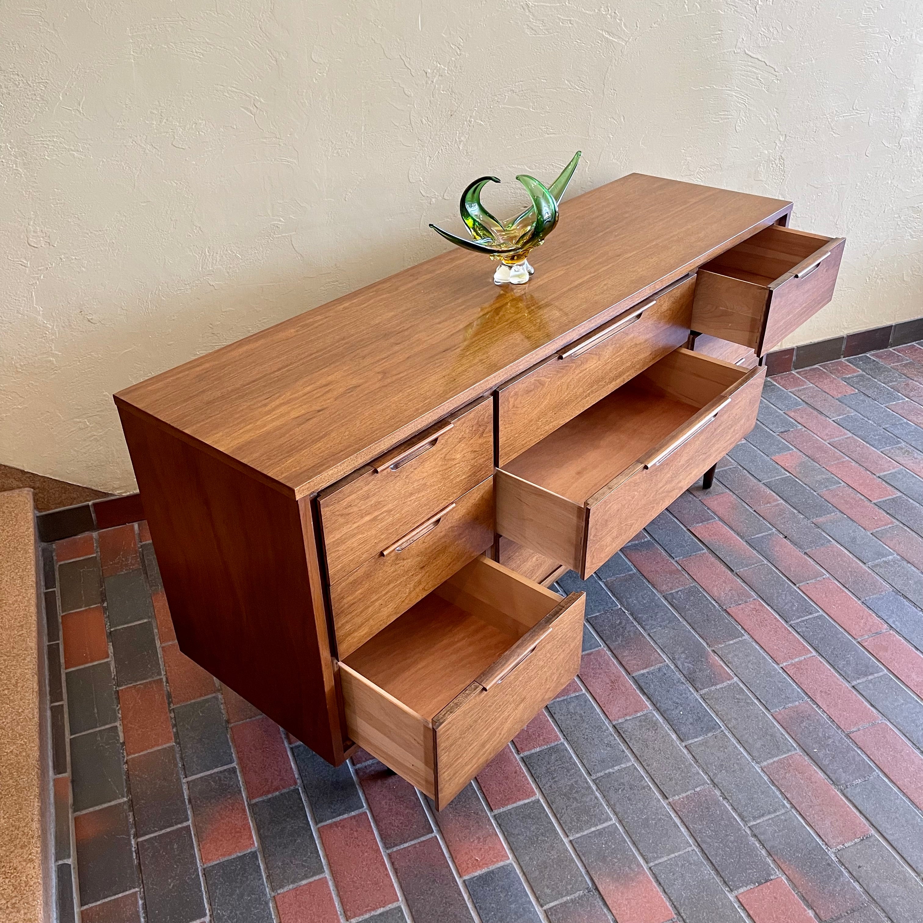 Enhance your bedroom with this Vintage KRUG Walnut 9 Drawer Dresser. The warm, rich color of the walnut complements any decor. Its sleek handle pulls add a touch of elegance to the design. With 9 spacious drawers, this dresser provides ample storage. 