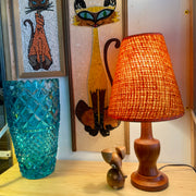 This small vintage solid teak lamp exudes mid-century charm. The original burnt orange shade adds a pop of retro flair, casting a soft, ambient glow.