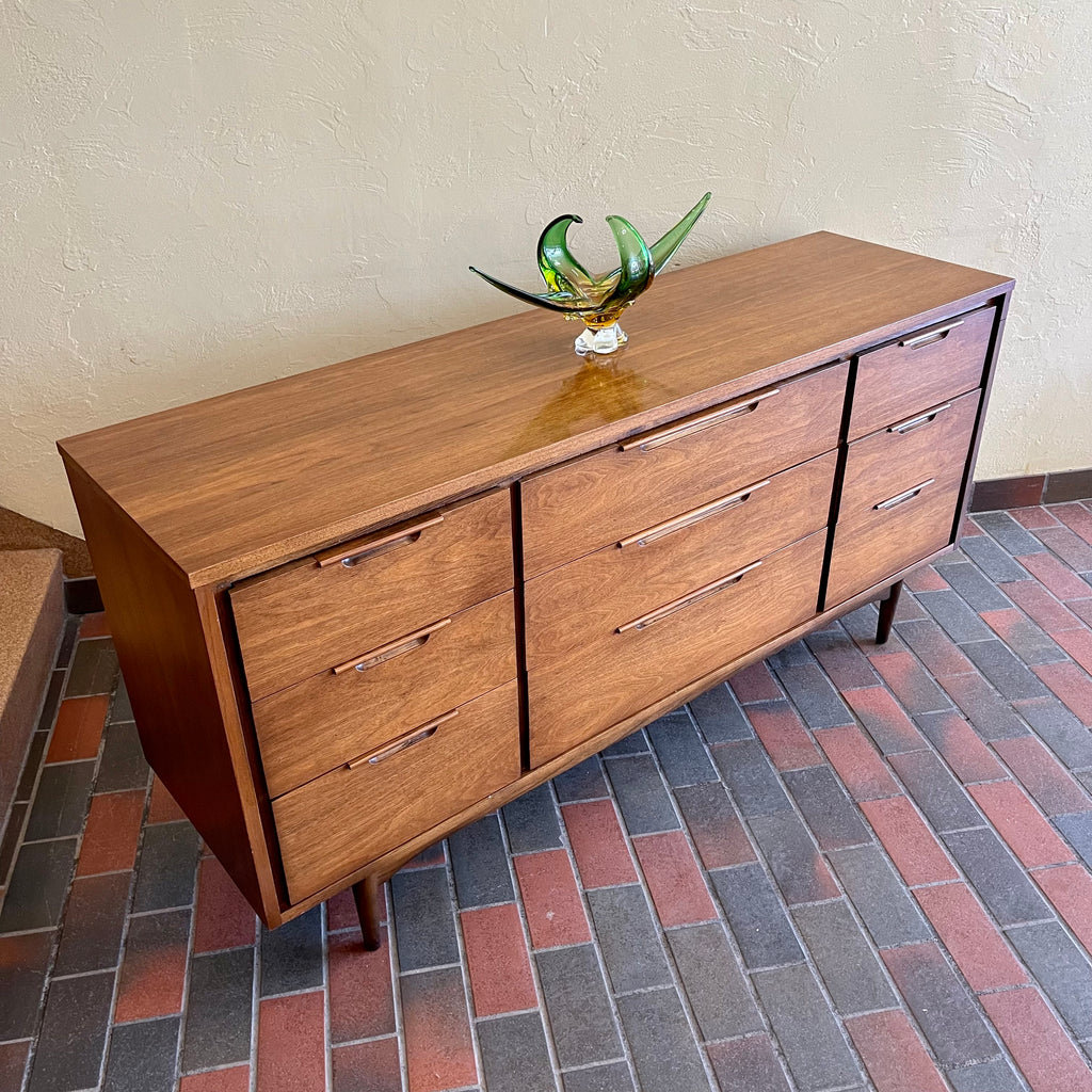 Enhance your bedroom with this Vintage KRUG Walnut 9 Drawer Dresser. The warm, rich color of the walnut complements any decor. Its sleek handle pulls add a touch of elegance to the design. With 9 spacious drawers, this dresser provides ample storage. 