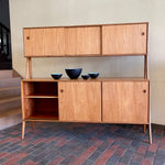 Load image into Gallery viewer, Two-tier Teak Danish Sideboard Credenza. The upper tier hosts a cabinet with sliding doors for storage. Below, sliding doors open to compartments with adjustable shelves, and drawers for small items. Solid sculptural teak legs tie the piece together. | Mr. Mansfield Vintage.
