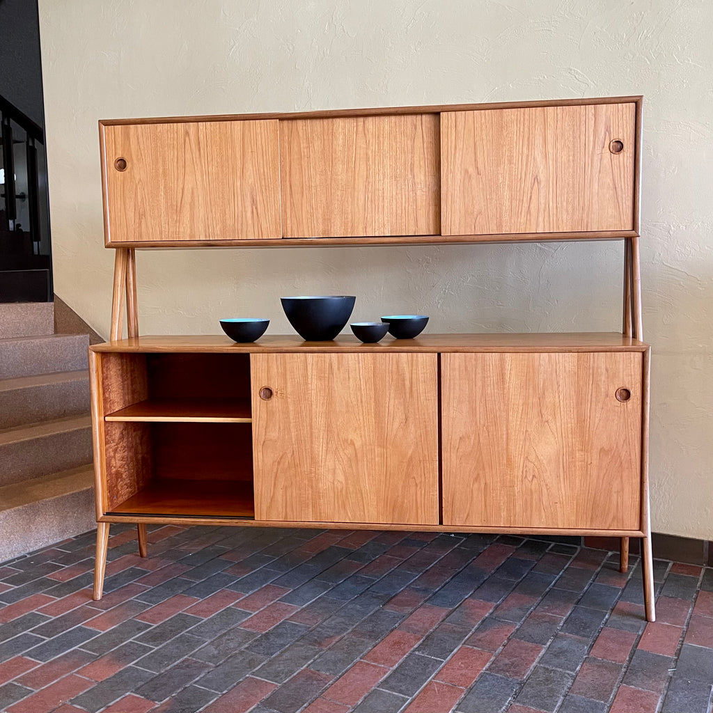 Two-tier Teak Danish Sideboard Credenza. The upper tier hosts a cabinet with sliding doors for storage. Below, sliding doors open to compartments with adjustable shelves, and drawers for small items. Solid sculptural teak legs tie the piece together. | Mr. Mansfield Vintage.