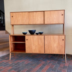 Two-tier Teak Danish Sideboard Credenza. The upper tier hosts a cabinet with sliding doors for storage. Below, sliding doors open to compartments with adjustable shelves, and drawers for small items. Solid sculptural teak legs tie the piece together. | Mr. Mansfield Vintage.