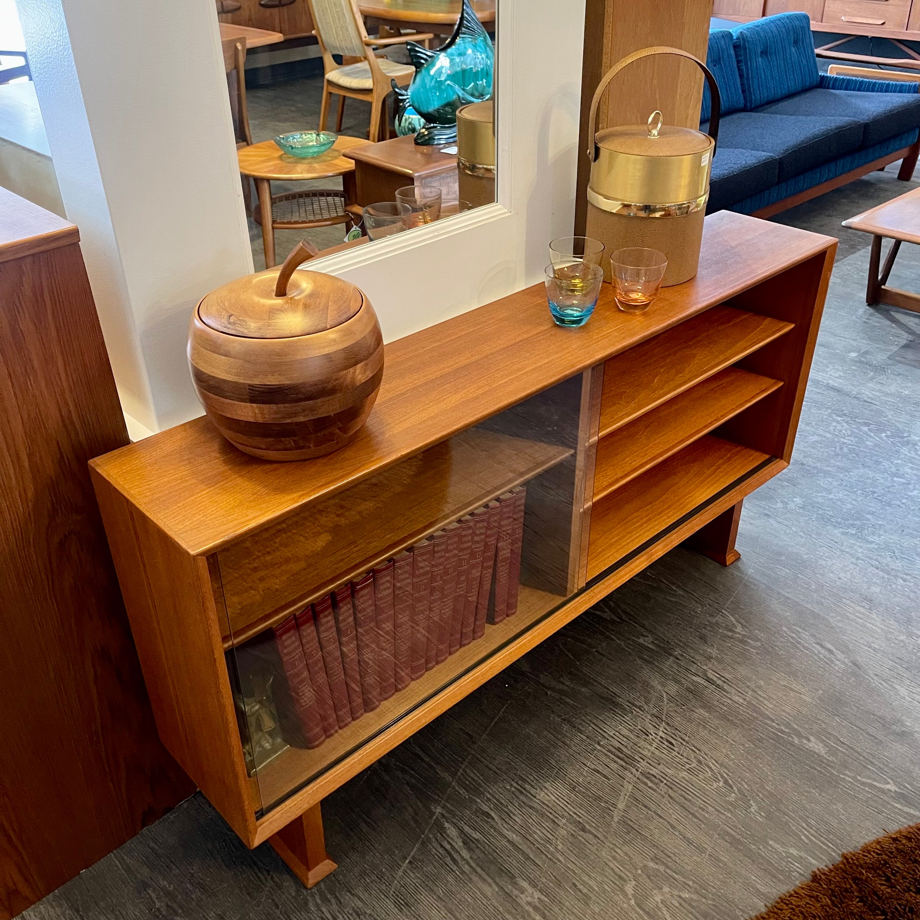 This 1960s Danish Mid Century Hutch exudes timeless elegance with its sleek design and functional features. It has three adjustable shelves, perfect for showcasing your most cherished items. The two sliding glass doors add a touch of sophistication while allowing easy access to your display pieces.