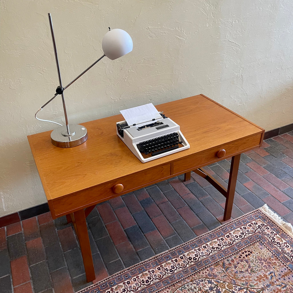  This Mid Century Danish Teak Desk epitomizes timeless design with its sleek lines and warm teak wood. Featuring two drawers, it offers practical storage while maintaining a minimalist aesthetic.