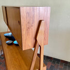 Two-tier Teak Danish Sideboard Credenza. The upper tier hosts a cabinet with sliding doors for storage. Below, sliding doors open to compartments with adjustable shelves, and drawers for small items. Solid sculptural teak legs tie the piece together. | Mr. Mansfield Vintage.
