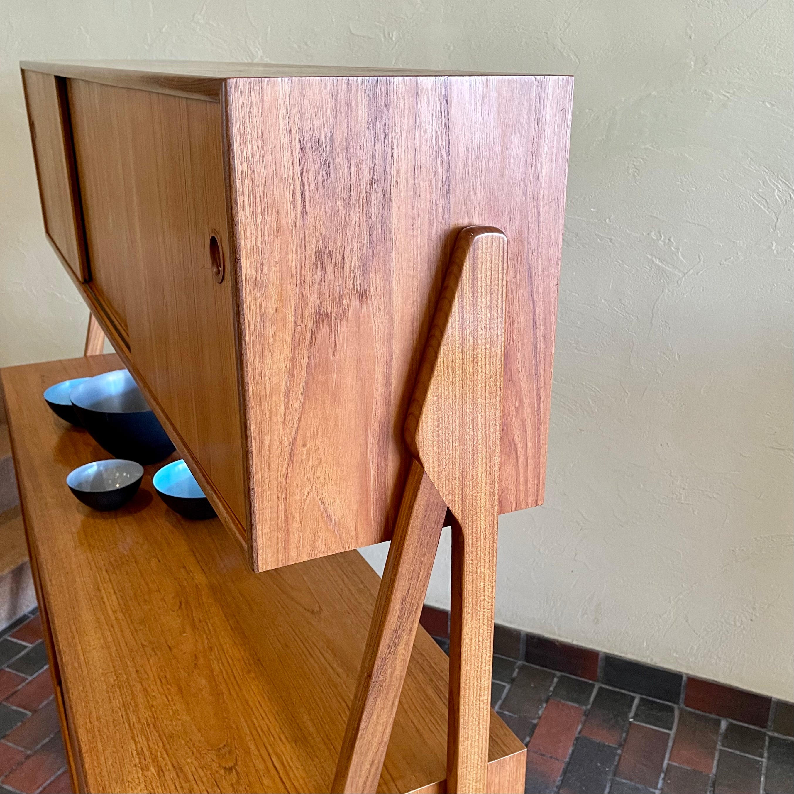 Two-tier Teak Danish Sideboard Credenza. The upper tier hosts a cabinet with sliding doors for storage. Below, sliding doors open to compartments with adjustable shelves, and drawers for small items. Solid sculptural teak legs tie the piece together. | Mr. Mansfield Vintage.