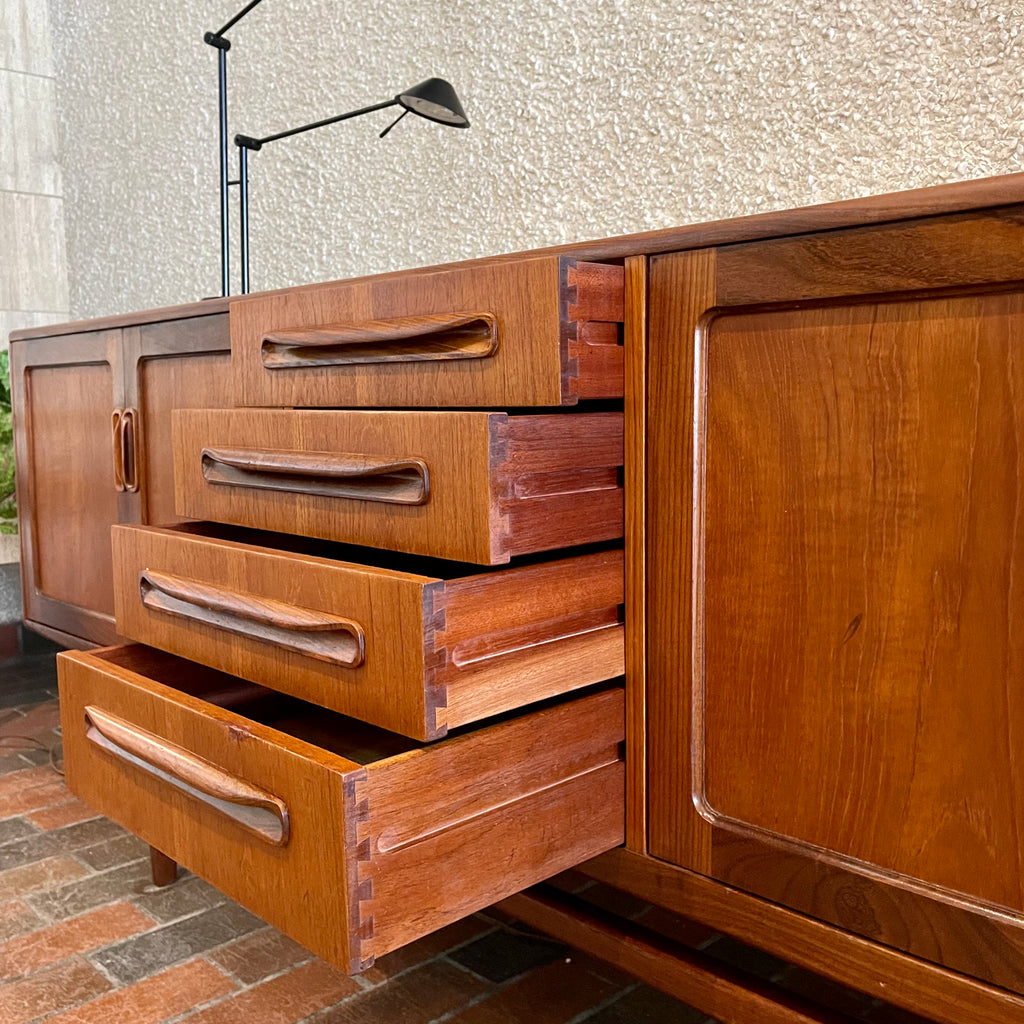 Crafted with attention to detail, this Mid Century Modern "Fresco" Teak Credenza by G Plan features four dovetail drawers for convenient storage, seamlessly integrated with additional storage on either side, offering even more organizational space.