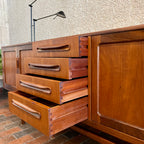Crafted with attention to detail, this Mid Century Modern "Fresco" Teak Credenza by G Plan features four dovetail drawers for convenient storage, seamlessly integrated with additional storage on either side, offering even more organizational space.