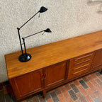Crafted with attention to detail, this Mid Century Modern "Fresco" Teak Credenza by G Plan features four dovetail drawers for convenient storage, seamlessly integrated with additional storage on either side, offering even more organizational space.