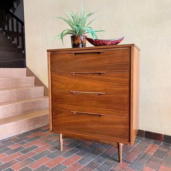 This Vintage KRUG Walnut Tallboy Dresser features four drawers and is made of rich dark walnut wood. Its classic design and high-quality construction make it a timeless addition to any bedroom. 