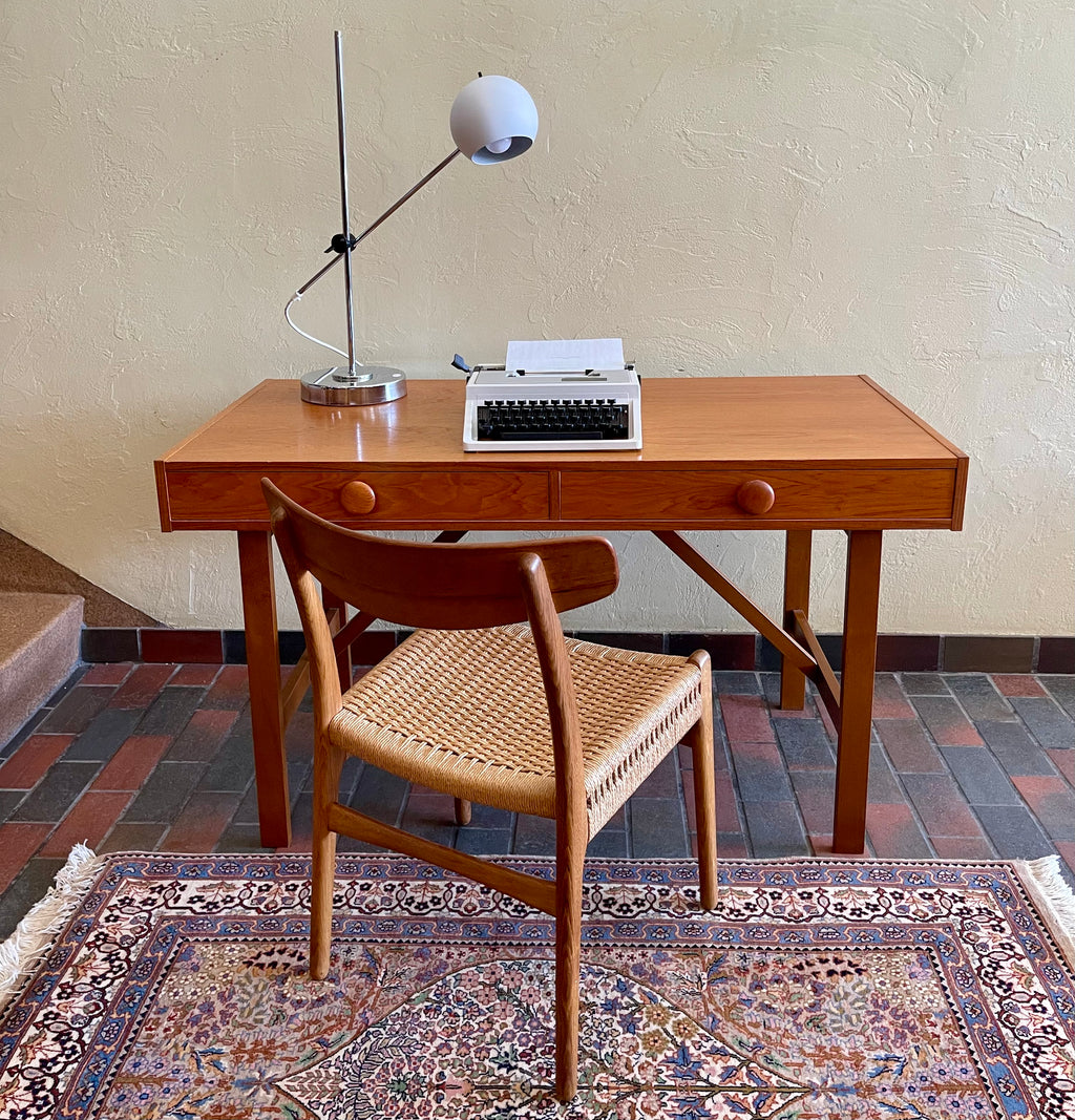  This Mid Century Danish Teak Desk epitomizes timeless design with its sleek lines and warm teak wood. Featuring two drawers, it offers practical storage while maintaining a minimalist aesthetic.