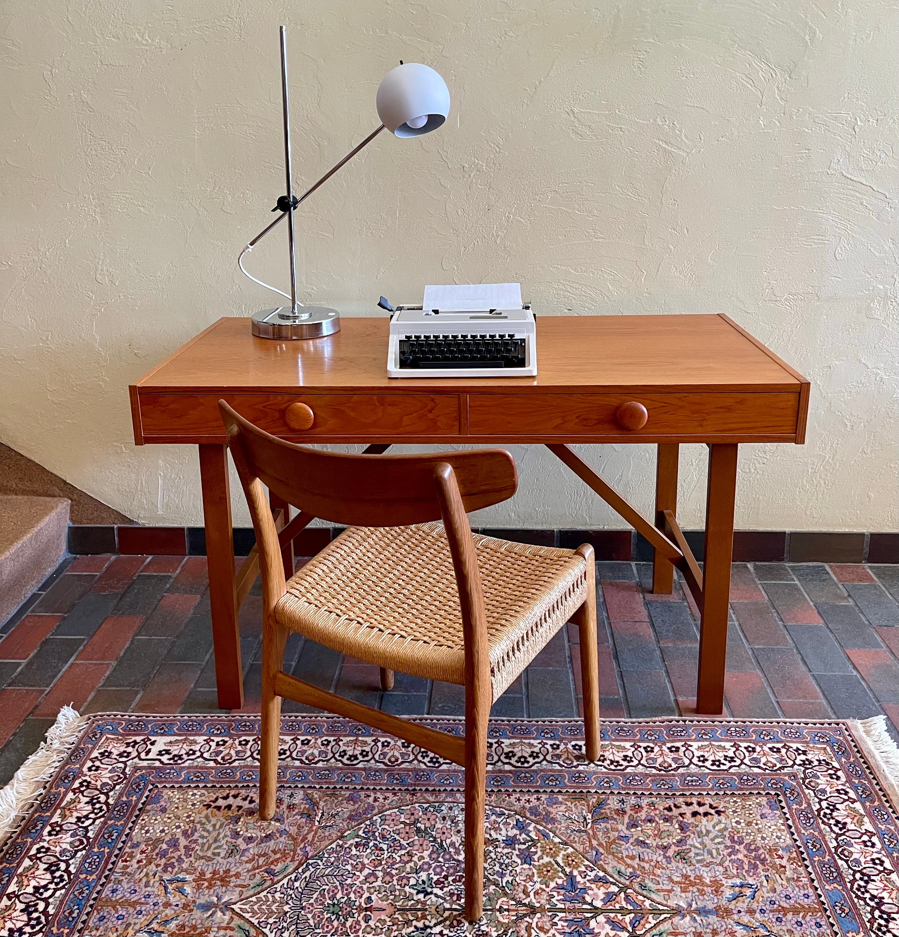  This Mid Century Danish Teak Desk epitomizes timeless design with its sleek lines and warm teak wood. Featuring two drawers, it offers practical storage while maintaining a minimalist aesthetic.