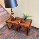 Load image into Gallery viewer, Teak G Plan nesting tables. Chrome Lamp with black shade, fern plant and an ashtray sits on top.There are 2 tables that pull out from under the main tablw. 