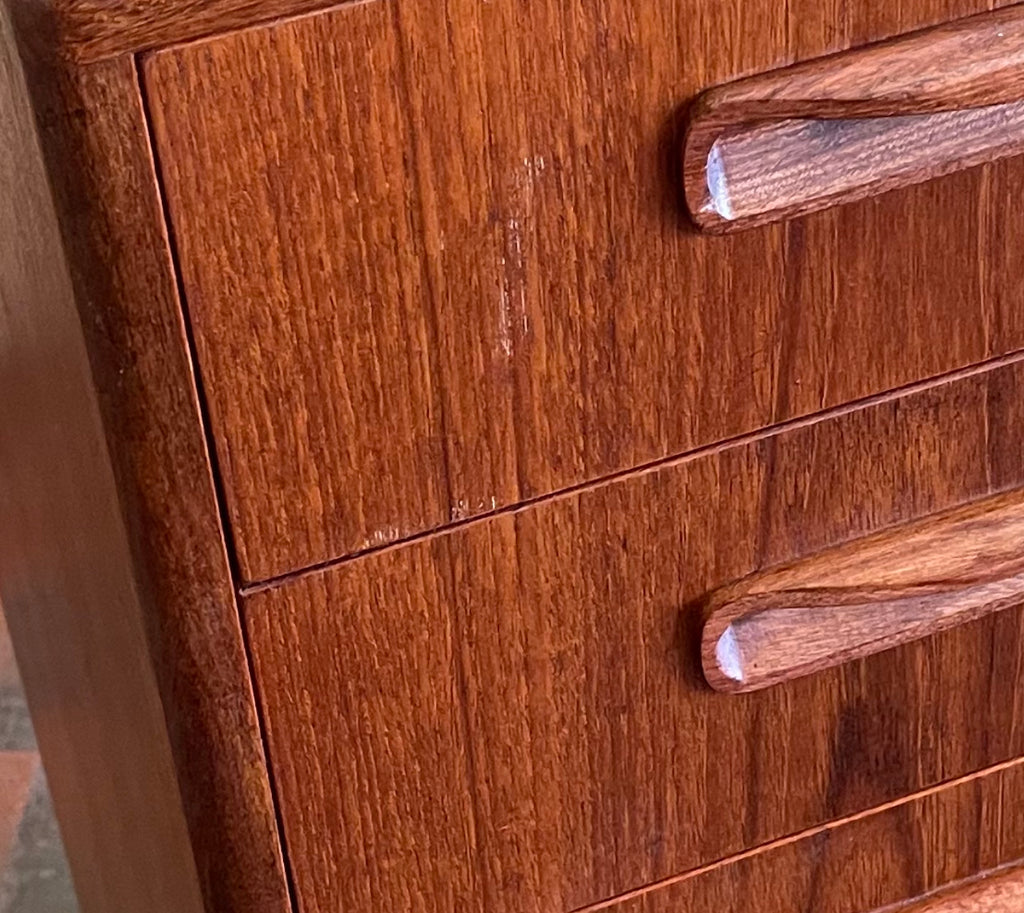 close up view of vintage teak chest of drawers showing light surface wear and scratch on the right side