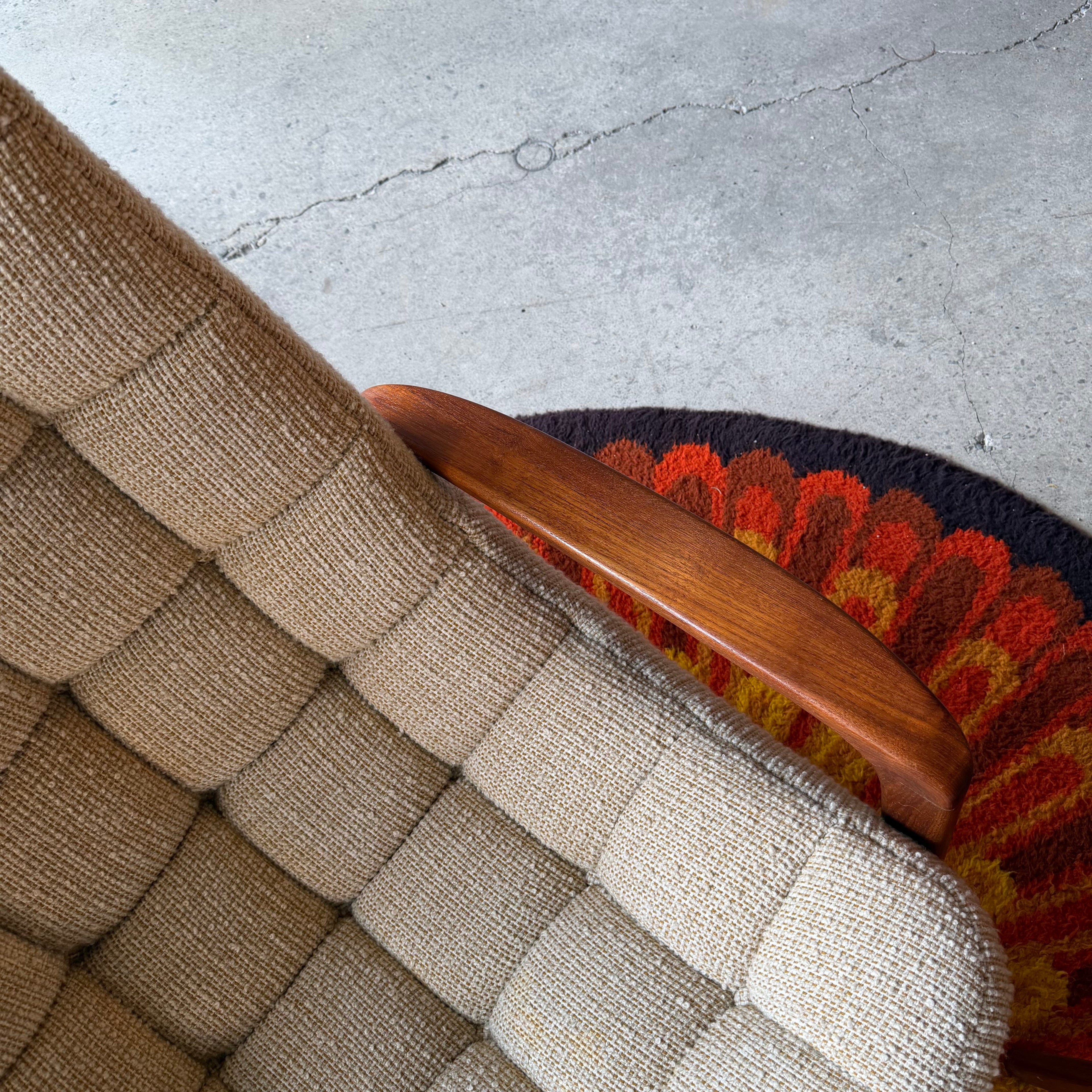 Close-up of sculpted teak armrest on a vintage Huber scoop chair, showing smooth curves and rich natural wood grain.