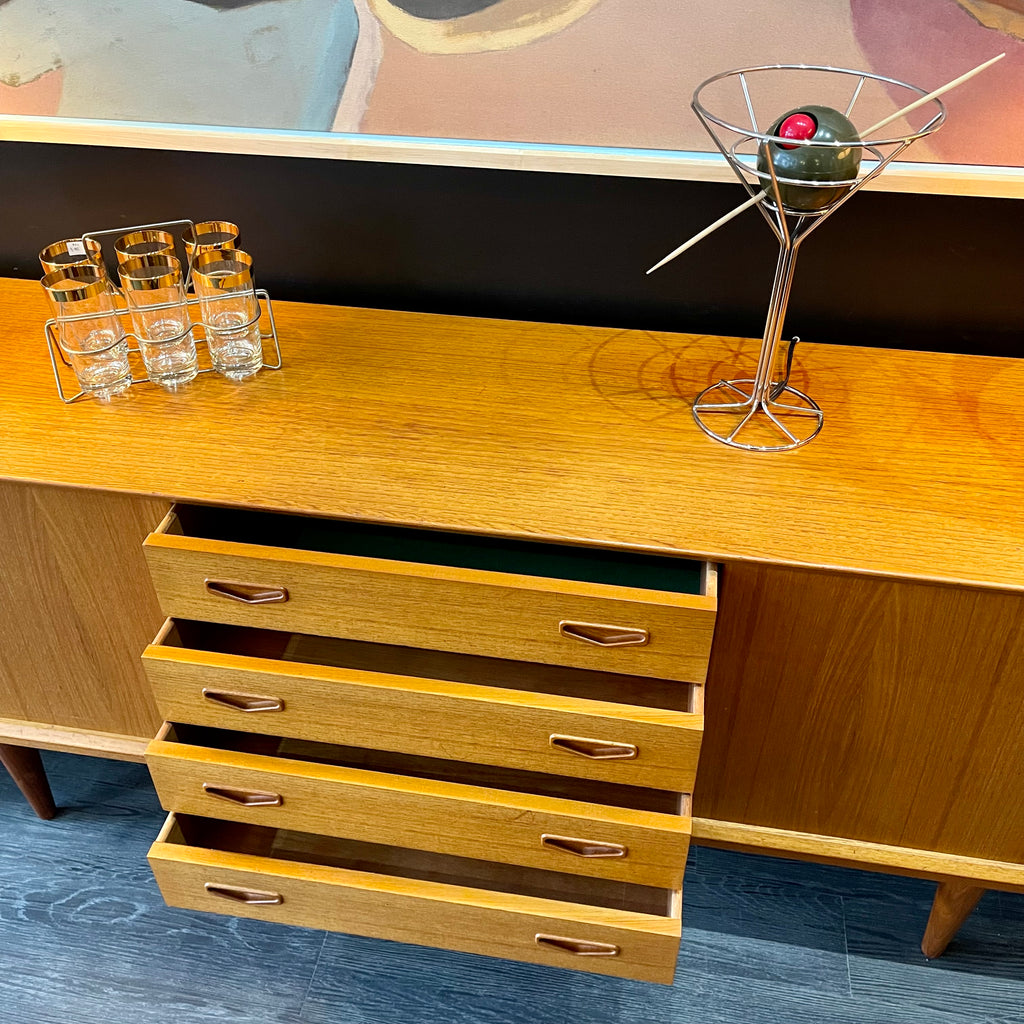 1960s Danish Teak Credenza is a beautiful blend of mid-century design and functionality. Crafted from teak, it features two sliding doors on either side that open to reveal ample storage space with adjustable shelving
