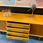 1960s Danish Teak Credenza is a beautiful blend of mid-century design and functionality. Crafted from teak, it features two sliding doors on either side that open to reveal ample storage space with adjustable shelving