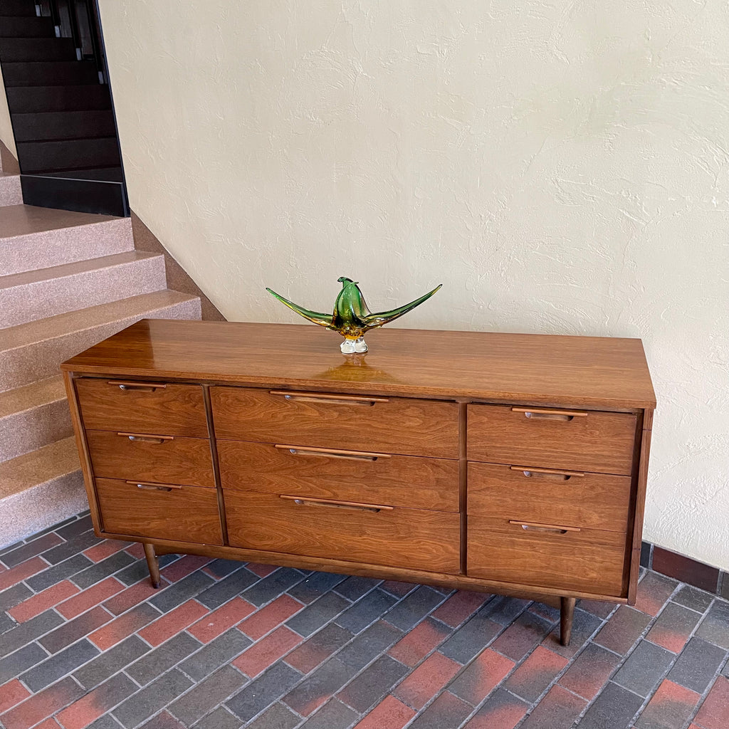 Enhance your bedroom with this Vintage KRUG Walnut 9 Drawer Dresser. The warm, rich color of the walnut complements any decor. Its sleek handle pulls add a touch of elegance to the design. With 9 spacious drawers, this dresser provides ample storage. 