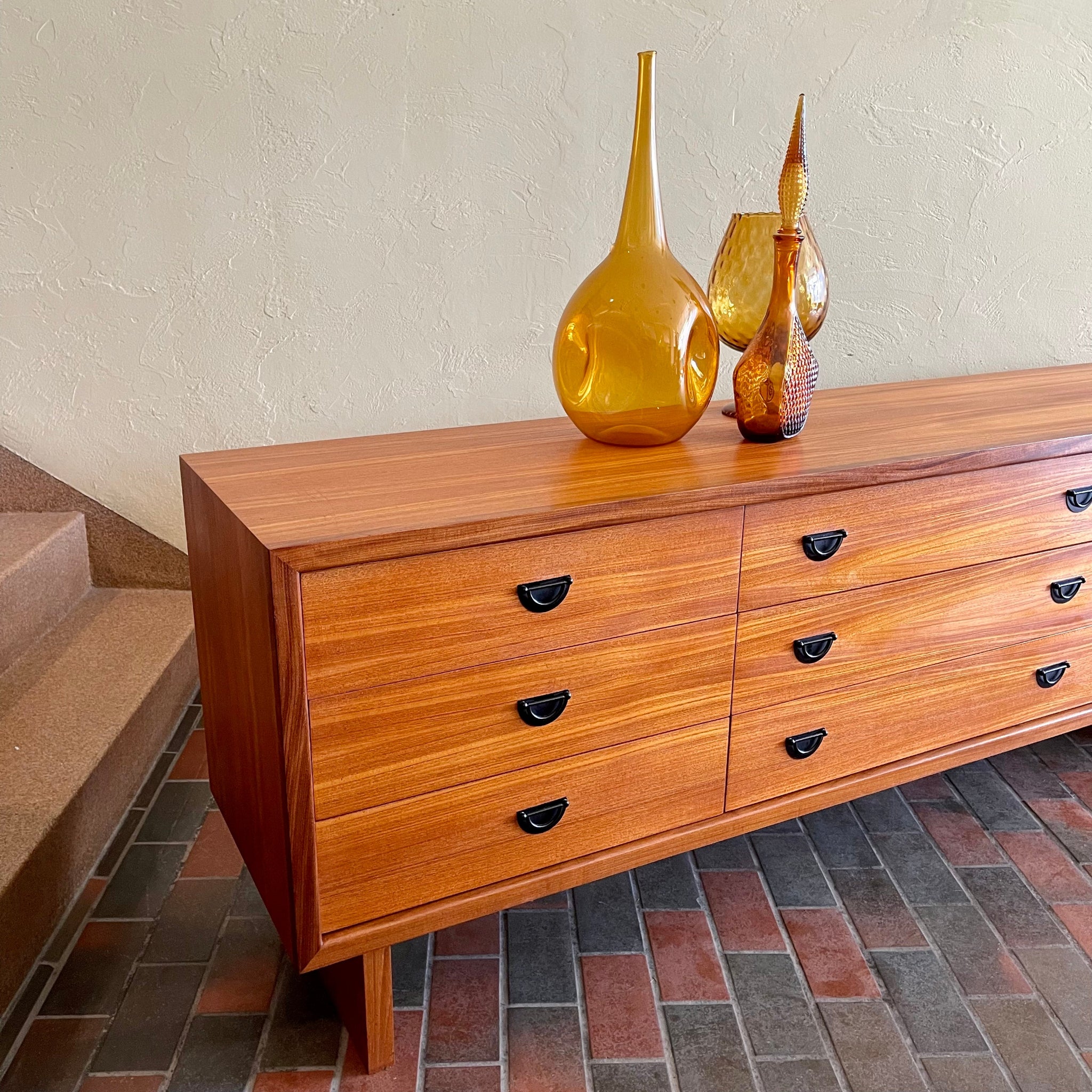 Angled view of R.S. Associates teak nine drawer dresser showing long low case and warm wood grain