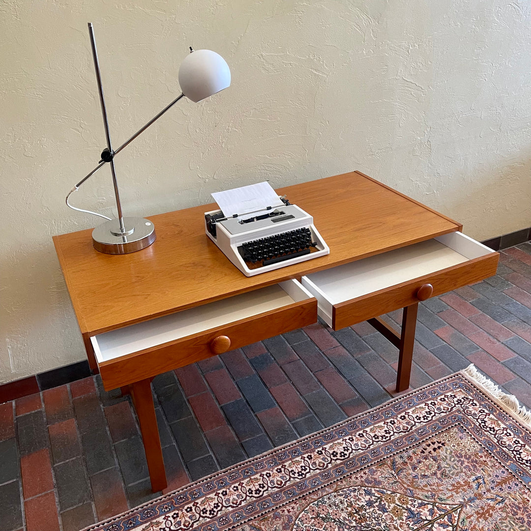  This Mid Century Danish Teak Desk epitomizes timeless design with its sleek lines and warm teak wood. Featuring two drawers, it offers practical storage while maintaining a minimalist aesthetic.