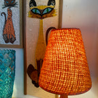 This small vintage solid teak lamp exudes mid-century charm. The original burnt orange shade adds a pop of retro flair, casting a soft, ambient glow.