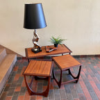 Teak G Plan nesting tables. Chrome Lamp with black shade, fern plant and an ashtray sits on top.There are 2 tables that pull out from under the main tablw. 