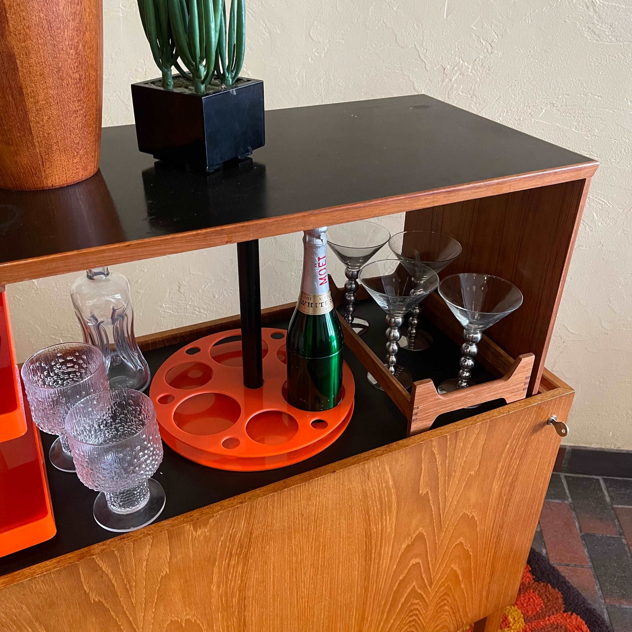 Interior of Danish teak pop-up bar cabinet showing bottle and glassware storage