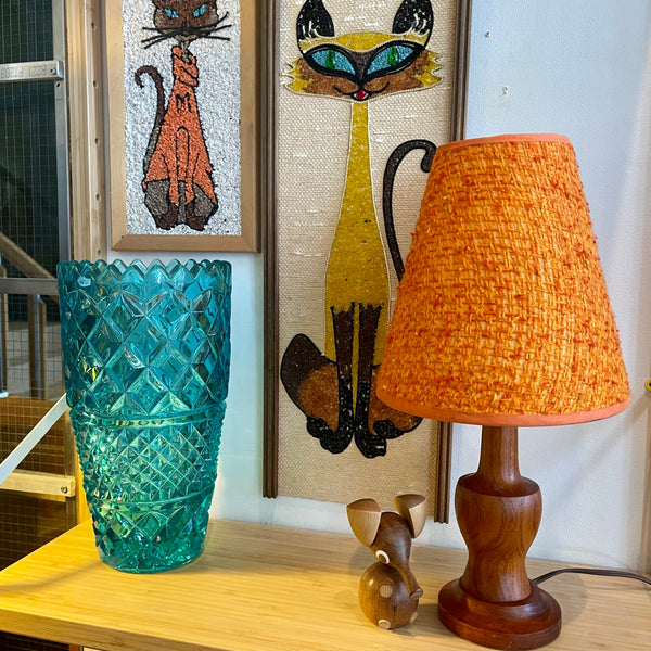 This small vintage solid teak lamp exudes mid-century charm. The original burnt orange shade adds a pop of retro flair, casting a soft, ambient glow.