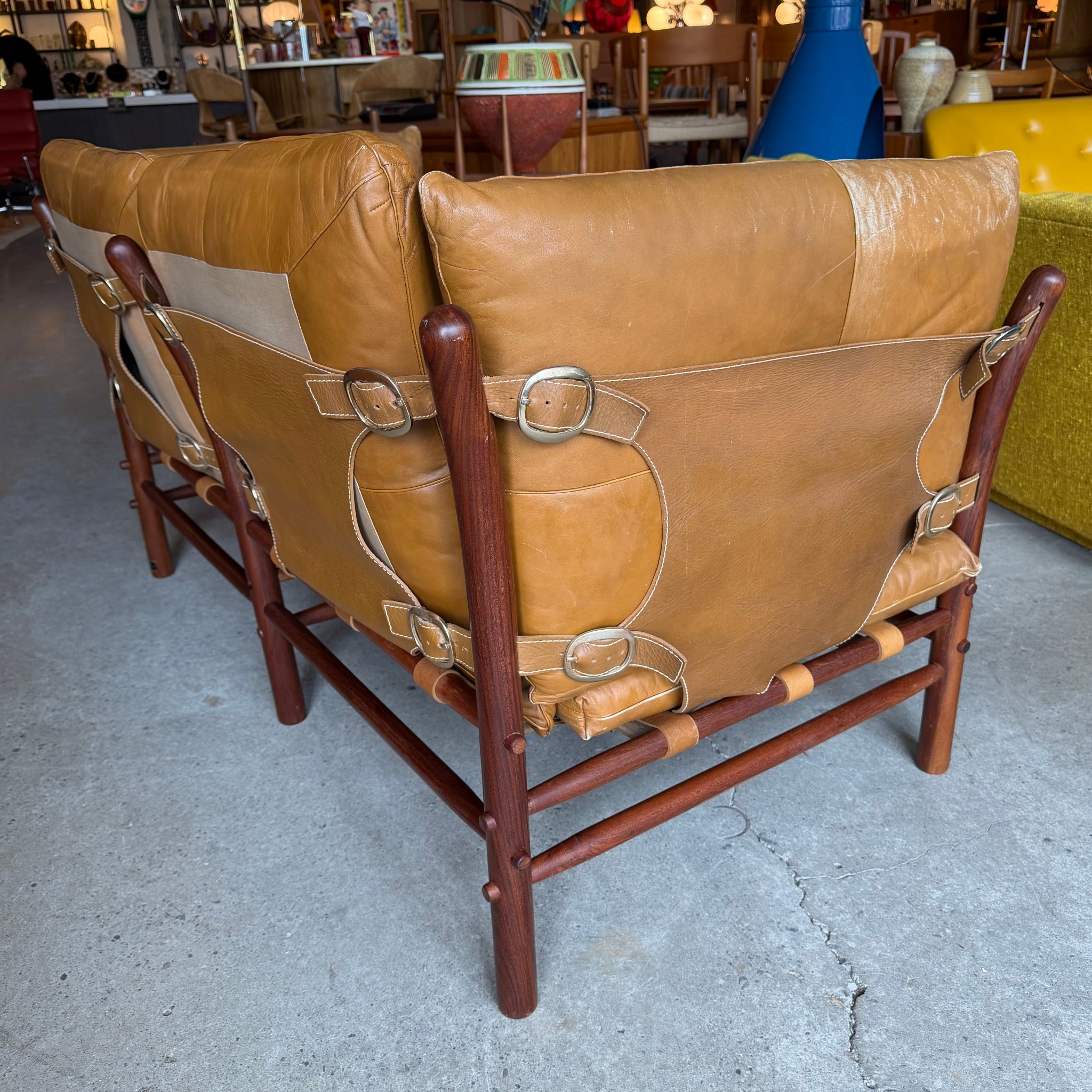 Rear view of leather sling loveseat with wood frame