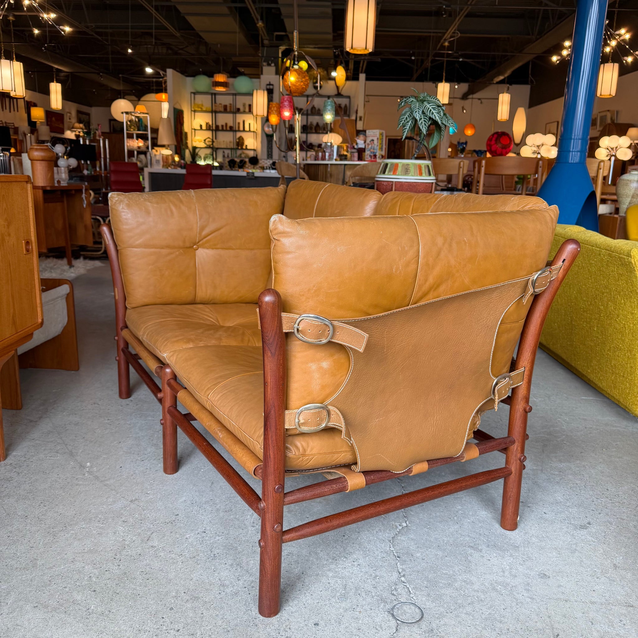 Side view of vintage leather loveseat with rosewood frame